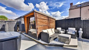 Ein überdachter Außenbereich mit Holzterrasse, Grill und Statue.