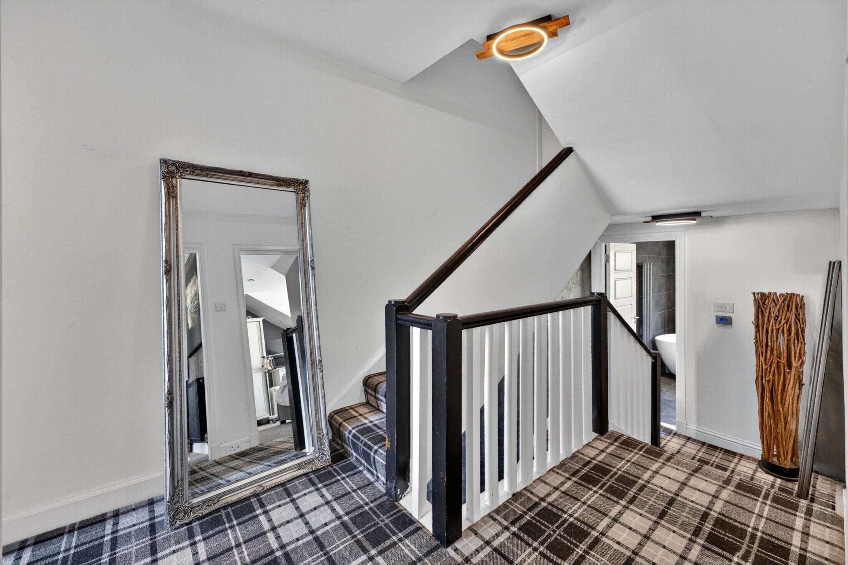 A staircase with a black handrail and white balusters, leading to a bathroom with a white toilet and a shower.
