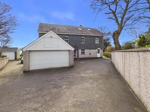 Il s’agit d’une propriété résidentielle dotée d’un garage, d’une allée et d’une maison à deux étages avec un toit en pente.