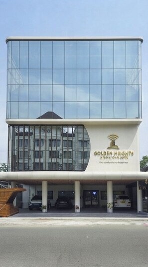 A modern hotel with a glass facade and a sign reading 'Golden Heights International Hotel.' - Hotel Golden Heights international (Ernakulam)