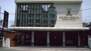 Et hotel med en moderne glasfacade og et skilt, der viser 'Golden Heights International Hotel'.