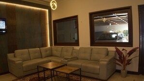 A living room with a sectional sofa, a coffee table, a large window, and a plant.