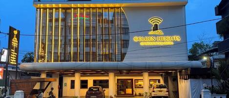 Un hotel moderno con fachada de vidrio y un cartel llamativo para 'Golden Heights International Hotel'.