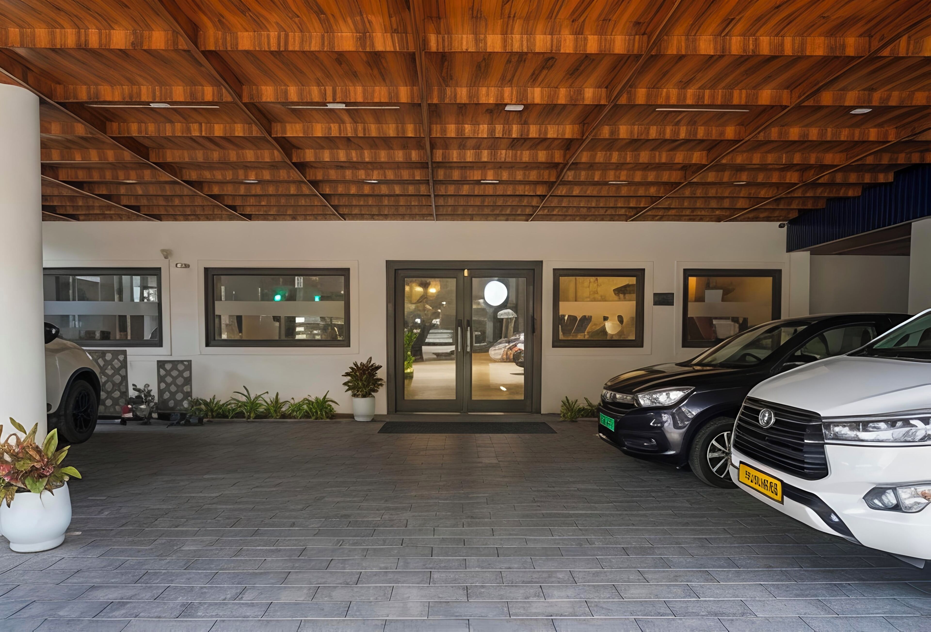 A building entrance with a wooden ceiling, a glass door, and a paved driveway.