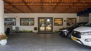 A building entrance with a wooden ceiling, a glass door, and a paved driveway.