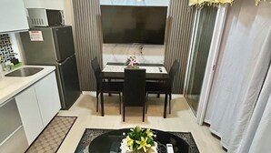 Een compacte leefruimte met een eethoek, kitchenette en een zithoek met een tafel en stoelen.