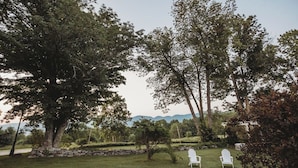 A grassy outdoor area with two white chairs and a stone wall. - Hideaway Inn Franconia Notch (Sugar Hill)