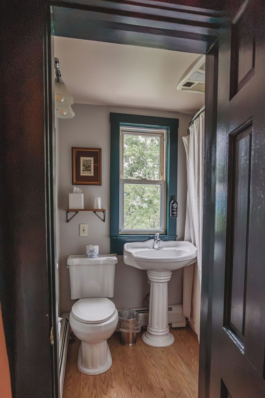 A small bathroom with a toilet, sink, and window.