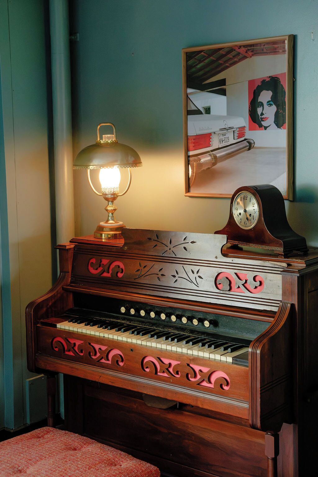 Un piano de madera con adornos decorativos, una lámpara y un reloj encima.