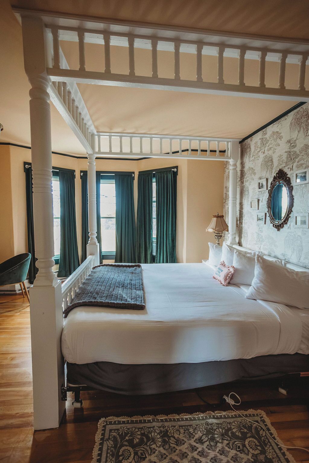 A bedroom with a four-poster bed, a large mirror, and a patterned rug.