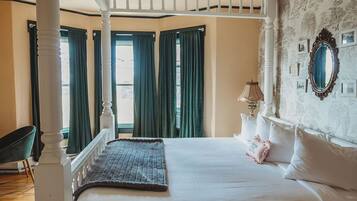 A bedroom with a four-poster bed, a large mirror, and a patterned rug.