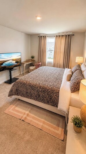 A hotel room with a large bed, a television, a desk, and a window with curtains. - Modern Greenville Townhome 3BR, 3BA, Arden Woods (Greenville)
