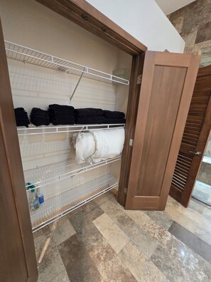 A storage closet with shelves, a door, and a tiled floor.