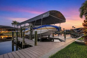 A boat docked at a marina with a covered area, wooden walkways, and a calm water body. - THE Luxury Villa, Gulf Access, Pool, Spa, Tiki Hut (Cape Coral)