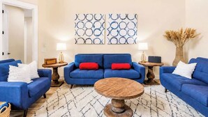 Un salon avec un canapé bleu, une table basse ronde et deux lampes fixées au mur.