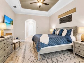 A bedroom with a bed, nightstands, a dresser, and a ceiling fan. - THE Luxury Villa, Gulf Access, Pool, Spa, Tiki Hut (Cape Coral)
