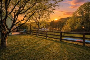 A fenced outdoor area with a grassy field, a bench, and a building in the background. - Luxe 2BR Cabin Private Pickleball, Hot Tub, Golf (Pigeon Forge)
