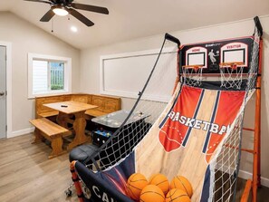 A basketball arcade with two hoops, a wooden table, and a bench. - Luxe 2BR Cabin Private Pickleball, Hot Tub, Golf (Pigeon Forge)