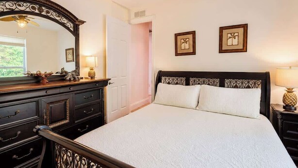 A bedroom with a large bed, a dresser, a mirror, and two framed pictures on the wall. - Naples Luxury Home, Resort Pool, Lanai, Fire Table (Naples)
