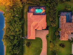 Eine Luftaufnahme einer Immobilie mit Swimmingpool, einer großen überdachten Terrasse und einem separaten Gebäude mit einem Ziegeldach.