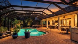 A covered outdoor area with a swimming pool, potted plants, and a dining area with tables and chairs. - Naples Luxury Home, Resort Pool, Lanai, Fire Table (Naples)