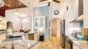 A modern kitchen with a marble countertop, stainless steel appliances, and a ceiling fan. - Naples Luxury Home, Resort Pool, Lanai, Fire Table (Naples)