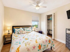 A bedroom with a bed, nightstands, a ceiling fan, a window with blinds, and a closet. - Port Charlotte Waterfront Luxe Tiki, Pool, Dock (Port Charlotte)