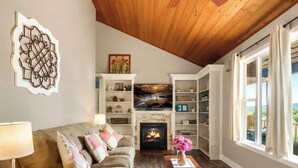 A cozy living room with a wooden ceiling, a fireplace, a sofa, a coffee table, and a bookshelf. - Secluded Mountain Paradise, Hot Tub, Firepit, View (Sevierville)