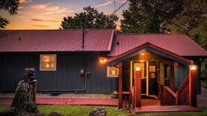 A rustic building with a red roof, a porch with a railing, and a small window. - Secluded Mountain Paradise, Hot Tub, Firepit, View (Sevierville)