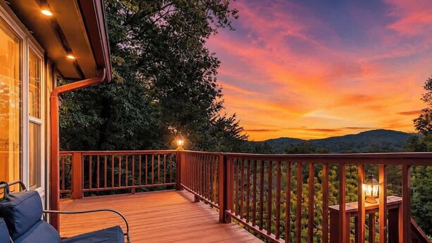 A wooden deck with a railing, a chair, and a table with a lamp. - Secluded Mountain Paradise, Hot Tub, Firepit, View (Sevierville)