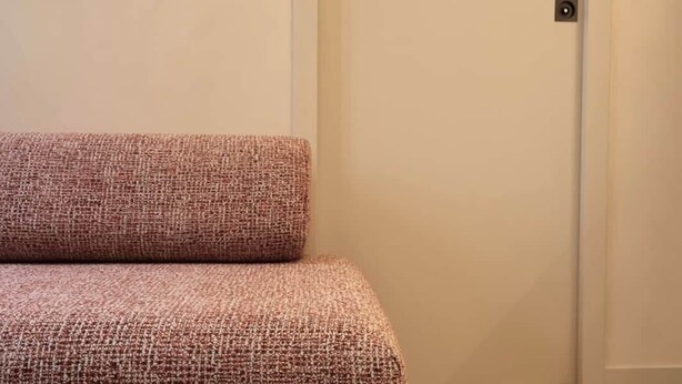 A room with a patterned sofa, a plain door, and a geometric patterned floor. - Architect-designed apartment near Beaugrenelle (Paris)