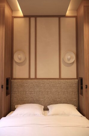 A hotel room with a bed, wooden headboard, and two wall sconces. - Architect-designed apartment near Beaugrenelle (Paris)