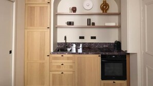 A compact kitchen with wooden cabinets, a built-in oven, and a marble countertop. - Architect-designed apartment near Beaugrenelle (Paris)