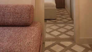 A hotel room with a bed, a patterned rug, a door leading to a bathroom, and a wall-mounted light fixture. - Architect-designed apartment near Beaugrenelle (Paris)
