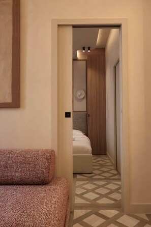 Ein Hotelzimmer mit einem Bett, einem gemusterten Teppich, einer Tür zu einem Badezimmer und einer Wandleuchte.