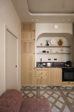A compact kitchen with wooden cabinets, a built-in oven, and a marble countertop. - Architect-designed apartment near Beaugrenelle (Paris)