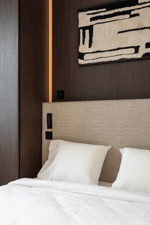 Ein Hotelzimmer mit einem Bett, einem Kopfteil und einem an der Wand befestigten Kunstwerk.
