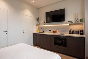 A modern kitchen with a built-in oven, a coffee machine, and a flat-screen TV above the counter. - Elegant Studio in the Vendôme - Madeleine Area (Paris)