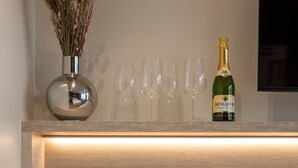 Et moderne køkken med en indbygget vask, en vase med tørrede blomster, en champagneflaske og en velkomstpakke.
