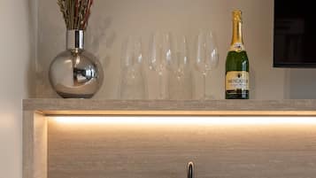 Una cocina moderna con un lavamanos empotrado, un jarrón con flores secas, una botella de champán y un kit de bienvenida.