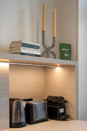 Eine Küchenarbeitsplatte mit Kaffeemaschine, Toaster, Wasserkocher und einem Stapel Bücher.