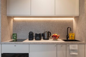 Eine moderne Küche mit eingebautem Herd, einer Kaffeemaschine, einem Wasserkocher und einer Obstschale auf der Arbeitsplatte.