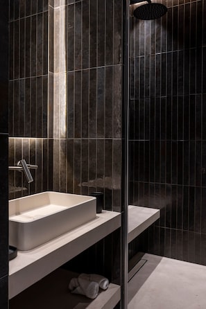 A modern bathroom with a rectangular sink, a handheld showerhead, and a towel on the floor. - Designer studio between the Opéra and Vendôme (Paris)
