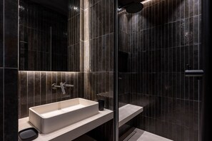 A modern bathroom with a rectangular sink, a handheld showerhead, and a glass-enclosed shower area.