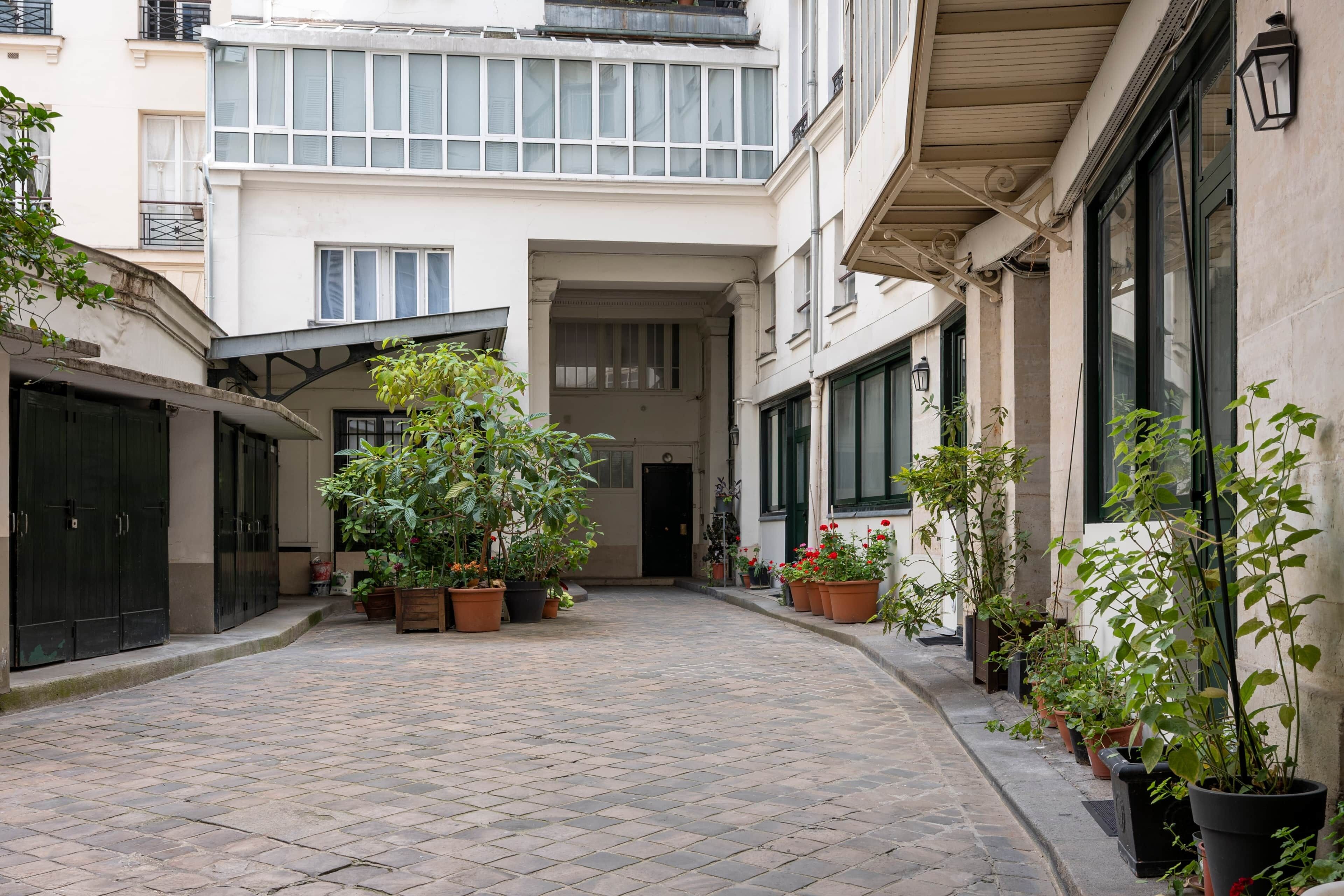A narrow alleyway with potted plants and a building entrance.