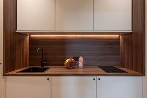 Eine moderne Küche mit einer Holzausziehtheke, einem schwarzen Wasserhahn, einer Obstschale und einer Saftflasche.