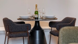 A dining area with a table set for two, a bottle of champagne, and a candle on a round table. - Deluxe Suite between Concorde and Vendôme (Paris)