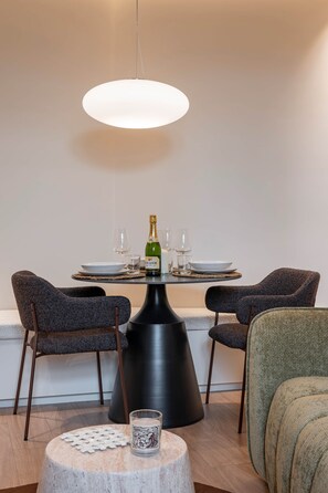 A dining area with a table set for two, a bottle of champagne, and a candle on a round table. - Deluxe Suite between Concorde and Vendôme (Paris)