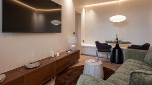 A modern living room with a flat-screen TV, a wooden console, a round coffee table, and a sofa. - Deluxe Suite between Concorde and Vendôme (Paris)