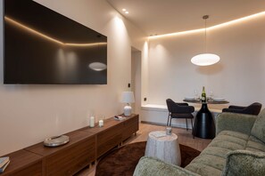 A modern living room with a flat-screen TV, a wooden console, a round coffee table, and a sofa. - Deluxe Suite between Concorde and Vendôme (Paris)